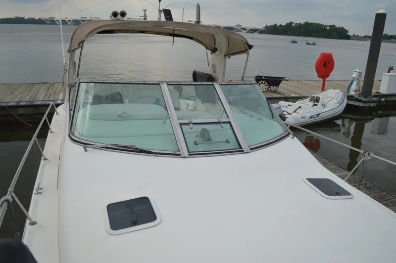Slide: The Image of 1998 Sea Ray 310 Sundancer docked at a marina, featuring a spacious deck and windshield. - 19