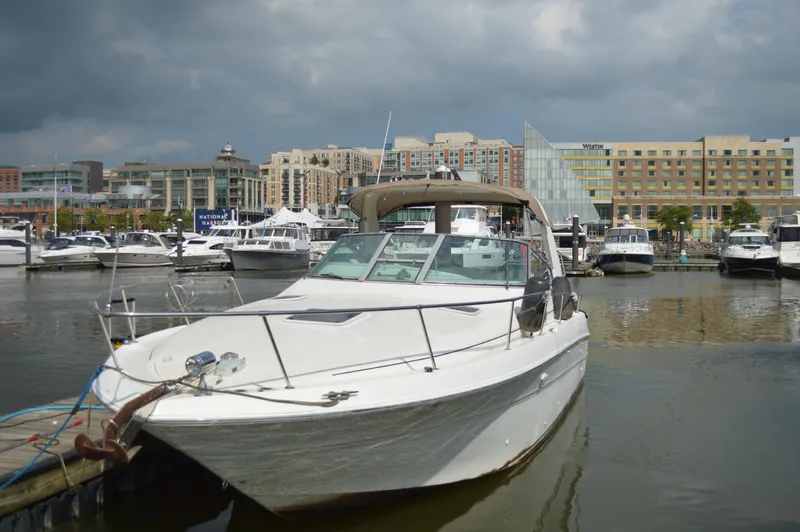 Slide: The Image of 1998 Sea Ray 310 Sundancer docked in a marina with cityscape background. - 3