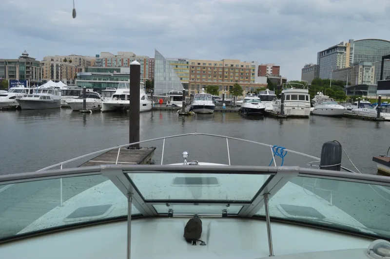 Slide: The Image of 1998 Sea Ray 310 Sundancer docked at a marina with cityscape background. - 35
