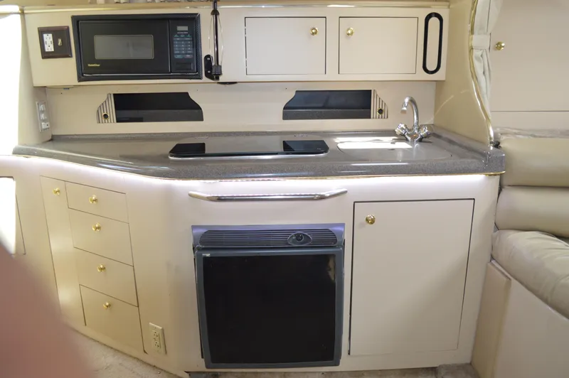 Slide: The Image of 1998 Sea Ray 310 Sundancer galley with microwave, sink, and storage cabinets. - 45