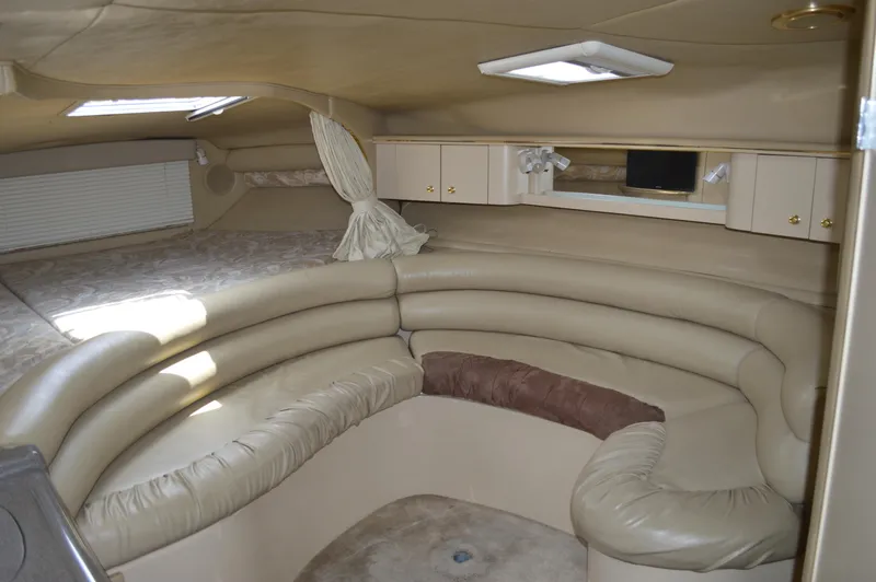 Slide: The Image of Interior of 1998 Sea Ray 310 Sundancer, featuring beige leather seating and cozy cabin layout. - 49