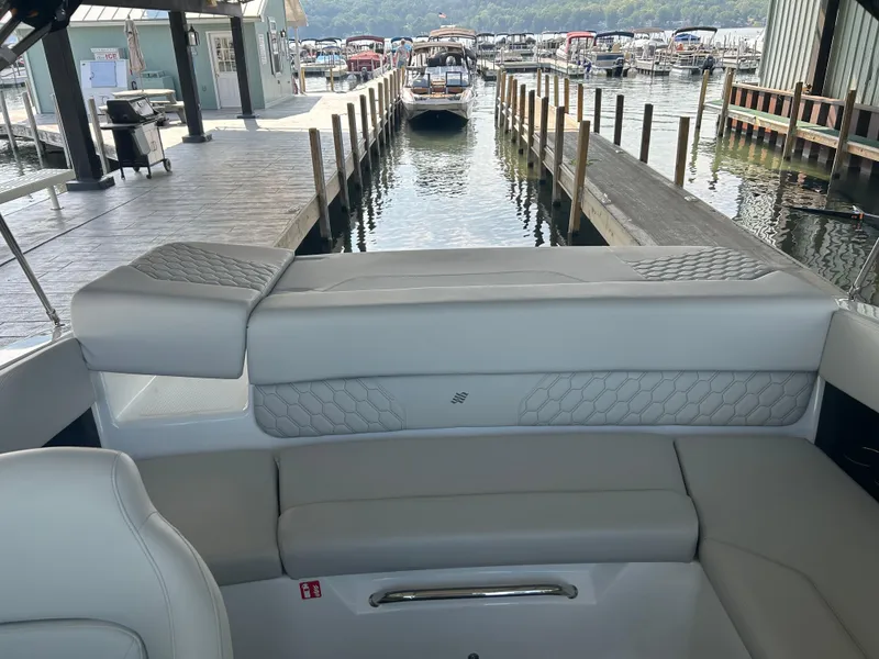 Slide: The Image of 2025 Four Winns H1 boat interior at a marina dock, featuring elegant seating. - 10
