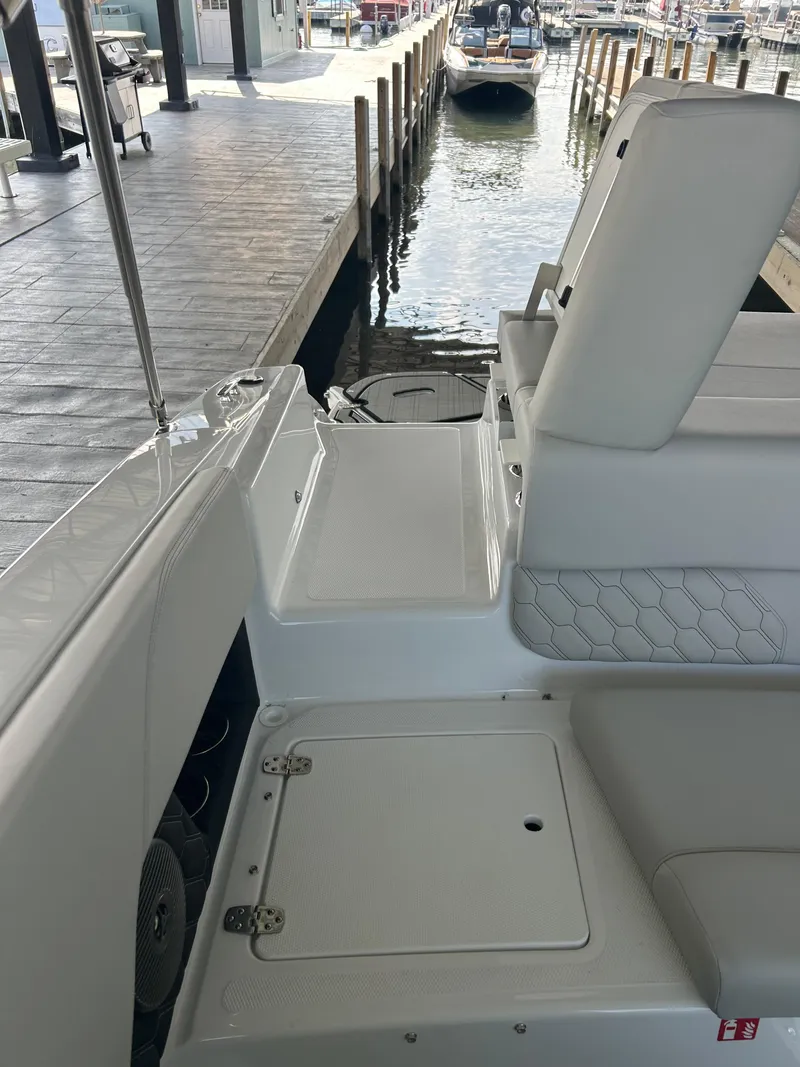 Slide: The Image of 2025 Four Winns H1 boat interior near dock, showcasing seating and storage. - 11