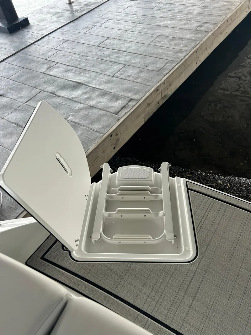 Slide: The Image of 2025 Four Winns H1 boat storage compartment with open hatch, dockside view. - 12