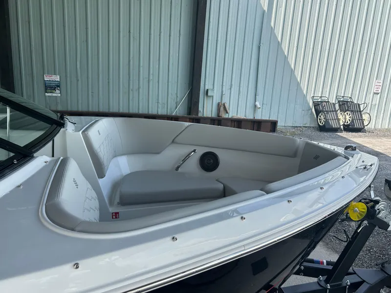 Slide: The Image of 2025 Four Winns H1 boat interior with white seating and speaker, docked near a metal building. - 4