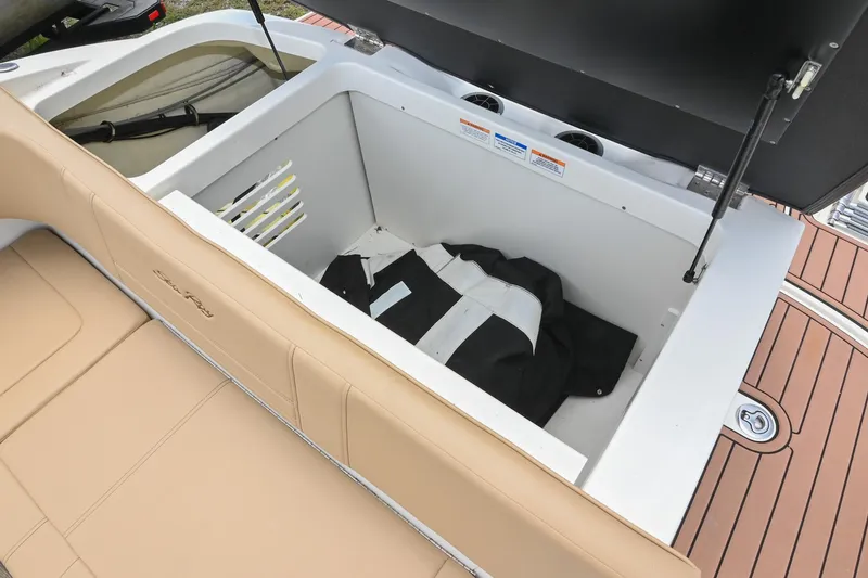 Slide: The Image of 2018 Sea Ray SPX 210 Outboard storage compartment with tan seating and black jacket inside. - 11