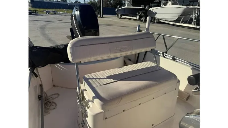 Slide: The Image of 2007 Boston Whaler 150 Montauk boat interior with seating and motor, docked outdoors. - 13