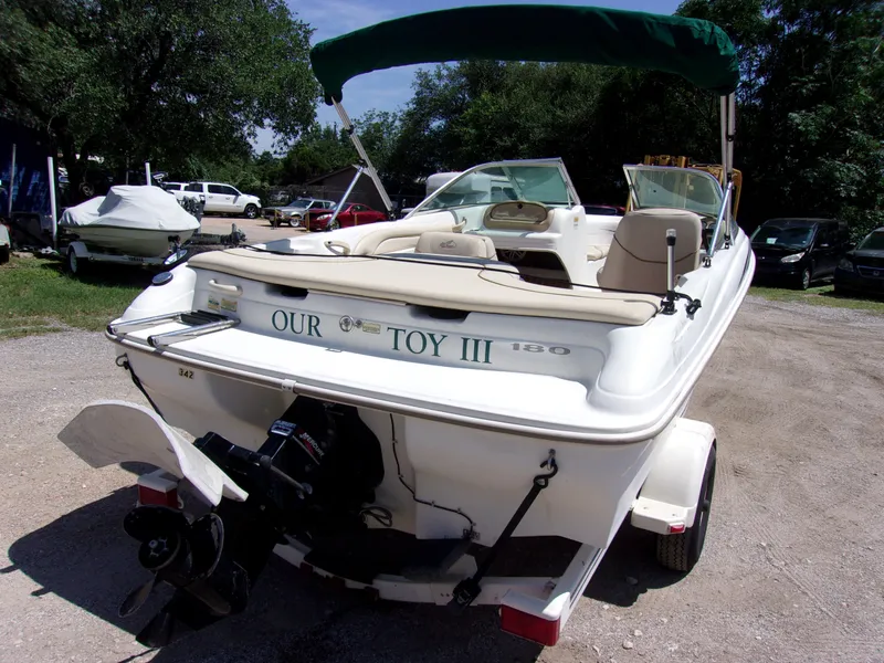 Slide: The Image of 2000 Sea Ray 180 Bow Rider boat with green canopy, parked on a trailer. - 4