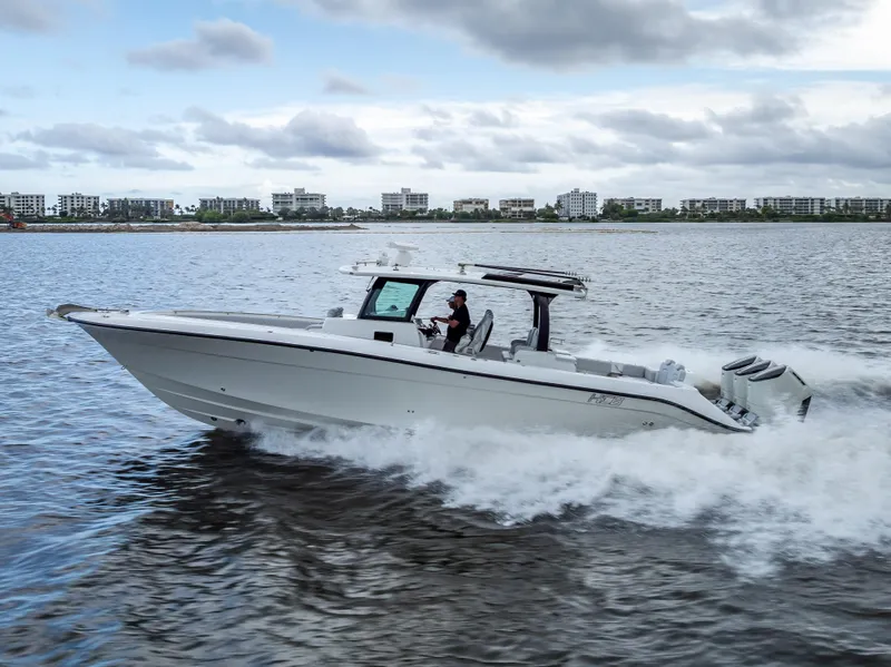 Slide: The Image of 2024 HCB 42 Lujo boat cruising on water with cityscape background. - 1