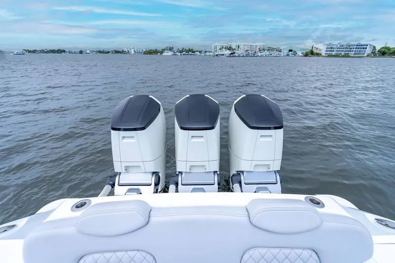 Slide: The Image of 2024 HCB 42 Lujo boat with triple outboard engines on a calm water backdrop. - 26