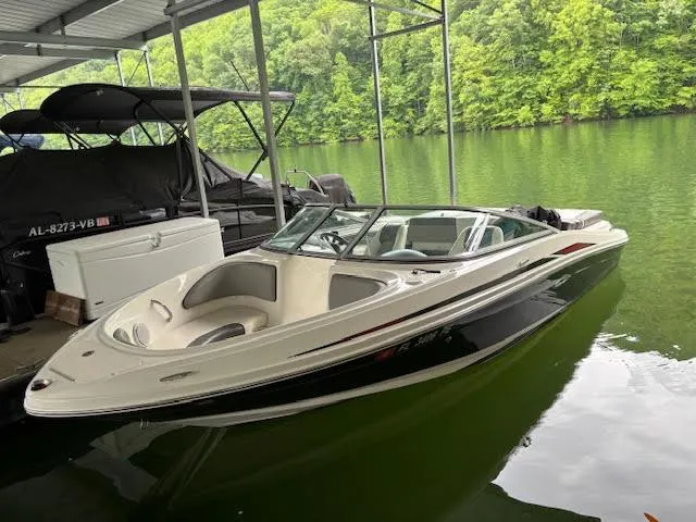 Slide: The Image of 2011 Sea Ray 205 Sport boat docked on a serene lake. - 2