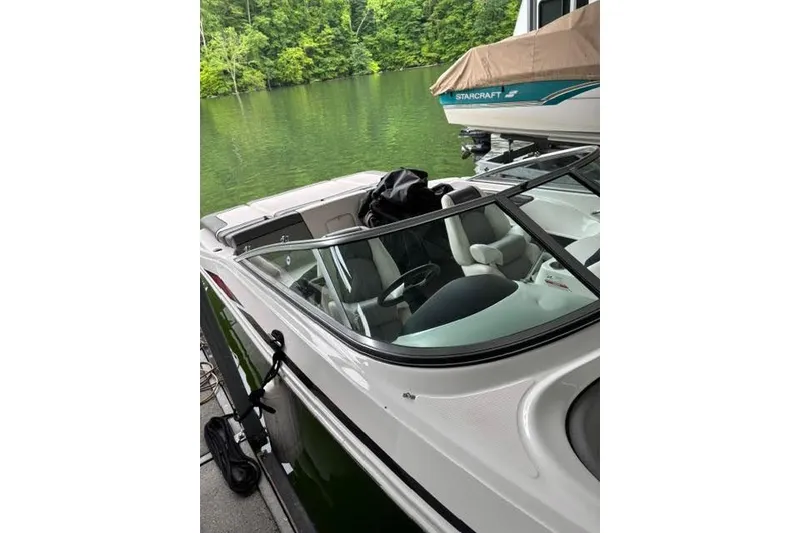 Slide: The Image of 2011 Sea Ray 205 Sport boat docked on a serene lake with lush greenery. - 22