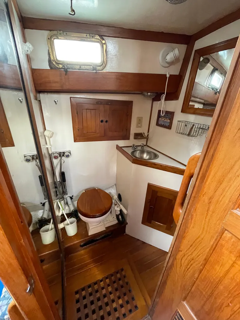 Slide: The Image of 1979 Formosa 46 Cutter bathroom with wooden cabinetry, sink, and porthole window. - 17