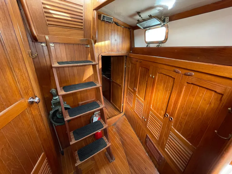 Slide: The Image of 1979 Formosa 46 Cutter interior with wooden stairs and cabinets, showcasing classic nautical design. - 18