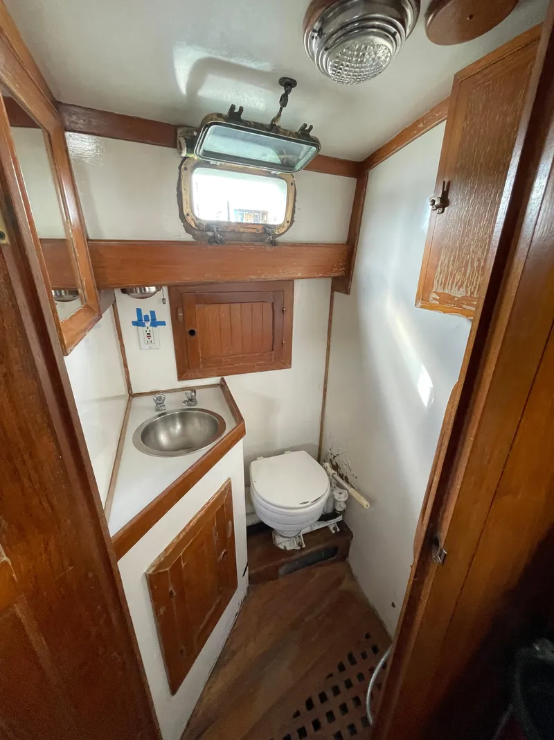 Slide: The Image of 1979 Formosa 46 Cutter bathroom with sink, toilet, wooden cabinetry, and porthole window. - 19