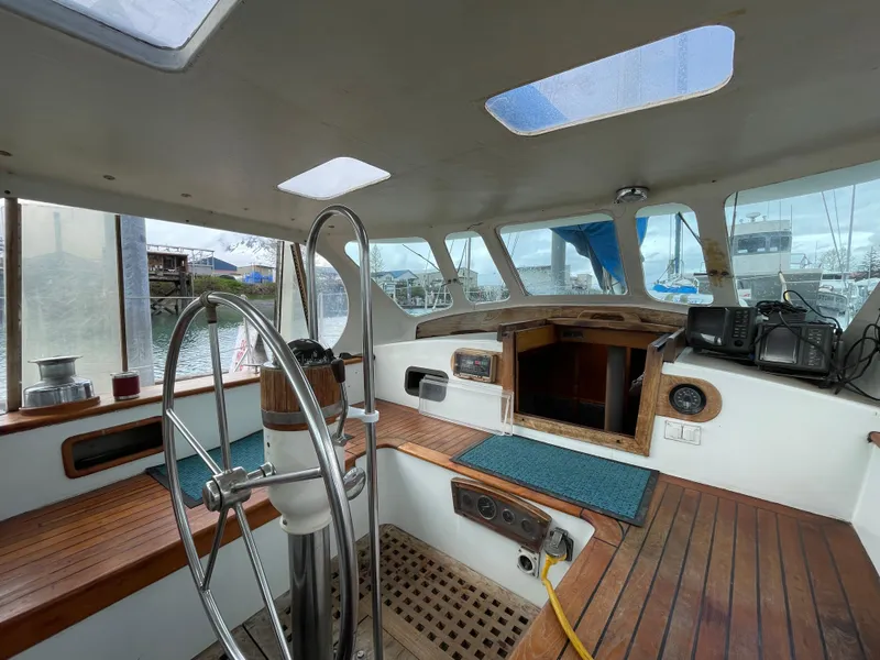 Slide: The Image of 1979 Formosa 46 Cutter cockpit with wooden seating, steering wheel, and nautical equipment. - 2