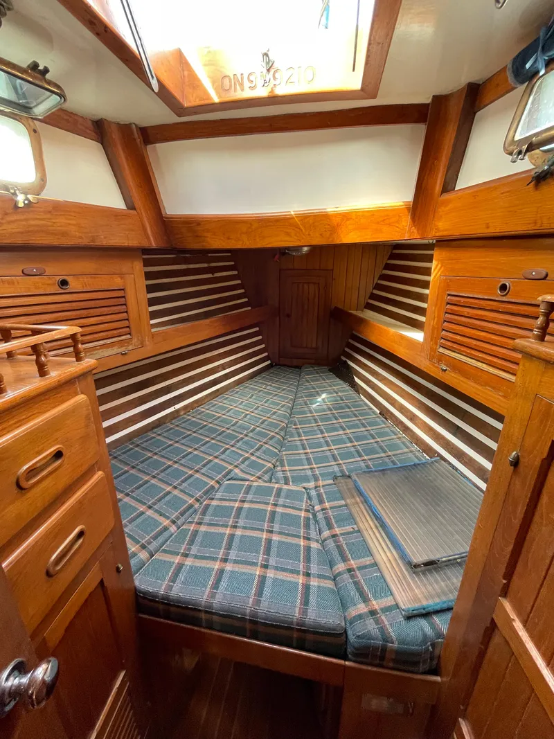 Slide: The Image of 1979 Formosa 46 Cutter cabin interior with wood paneling and plaid bedding. - 23