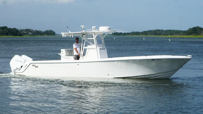 Slide: The Image of 2004 SeaVee 310B boat cruising on a calm river with a person at the helm. - 1