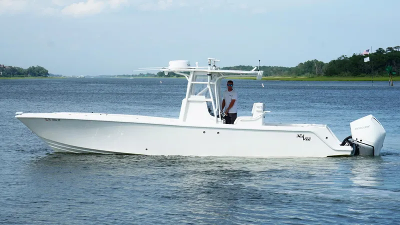 Slide: The Image of 2004 SeaVee 310B boat on calm water, side view, with a person at the helm. - 11