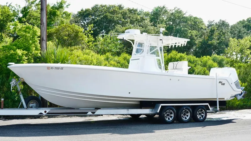 Slide: The Image of 2004 SeaVee 310B boat on trailer, parked outdoors with lush greenery in the background. - 12