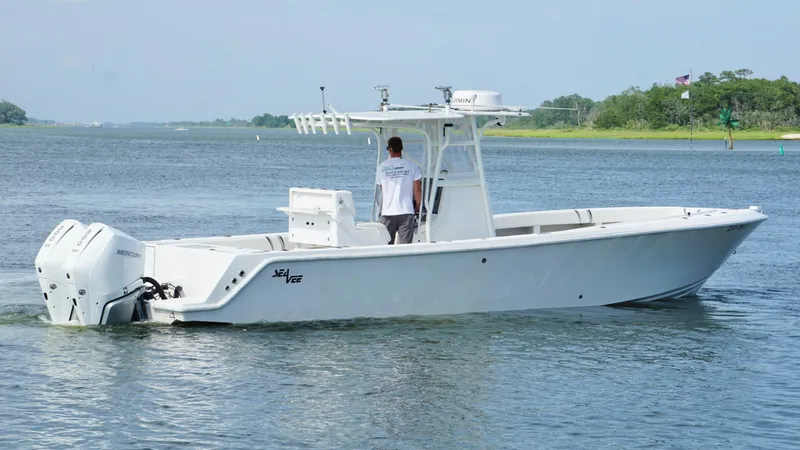 Slide: The Image of 2004 SeaVee 310B boat cruising on a calm river with lush green shoreline. - 7
