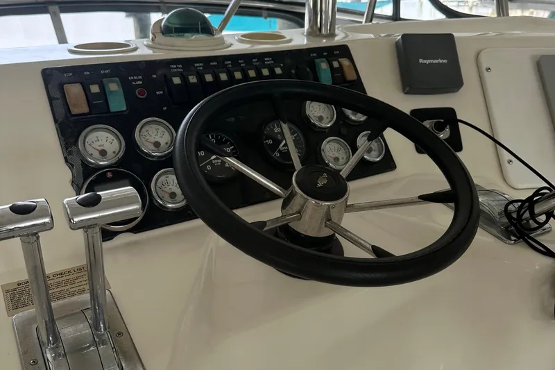 Slide: The Image of Steering wheel and dashboard of a 2002 Riviera 350 boat, featuring gauges and controls. - 14