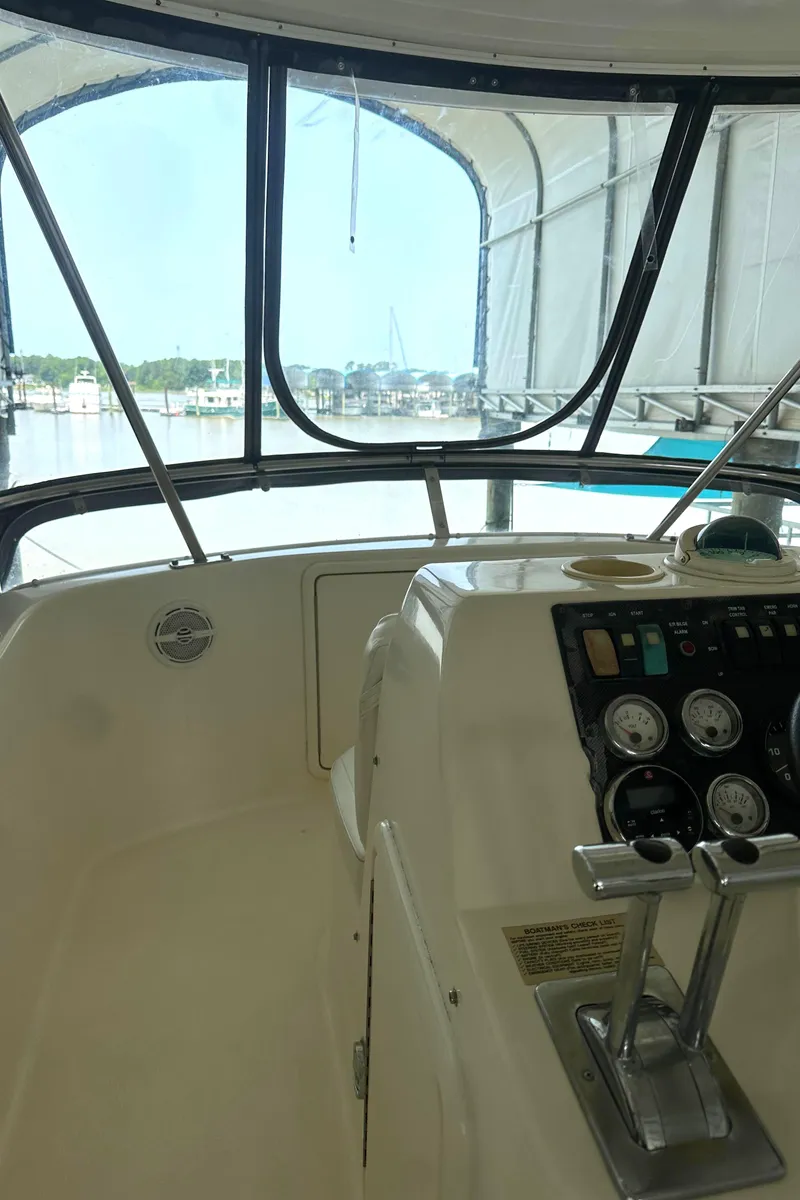 Slide: The Image of 2002 Riviera 350 boat cockpit with steering controls and gauges, docked at a marina. - 16