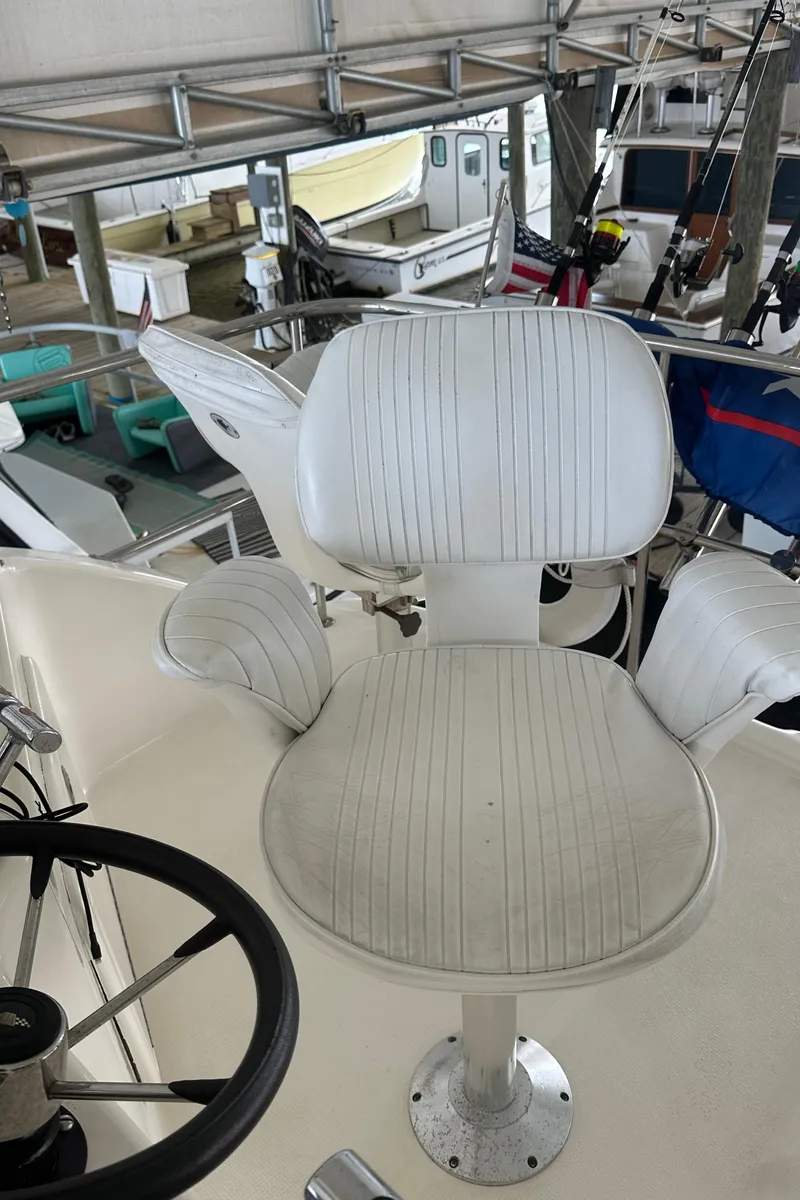 Slide: The Image of Captain's chair on 2002 Riviera 350 yacht, featuring white upholstery and helm controls. - 19
