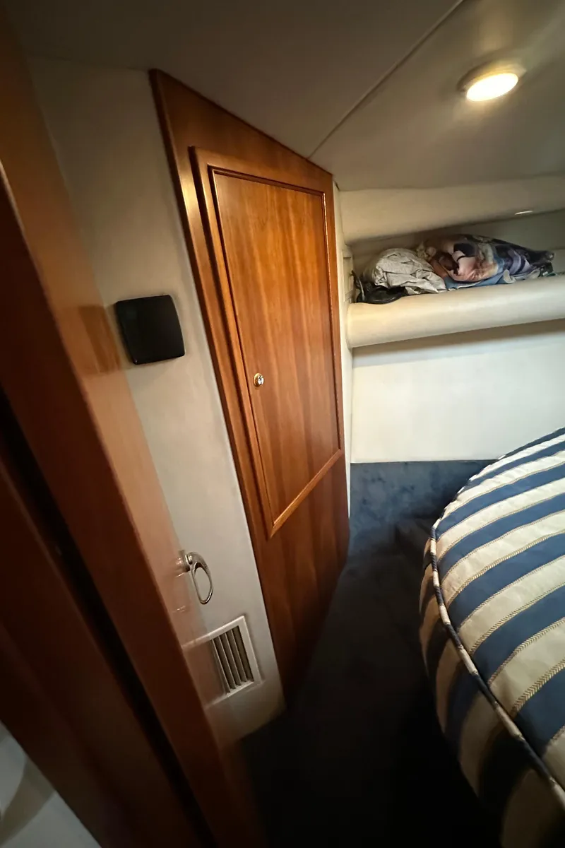 Slide: The Image of Interior of 2002 Riviera 350 yacht with wooden cabinet and striped bedding. - 25