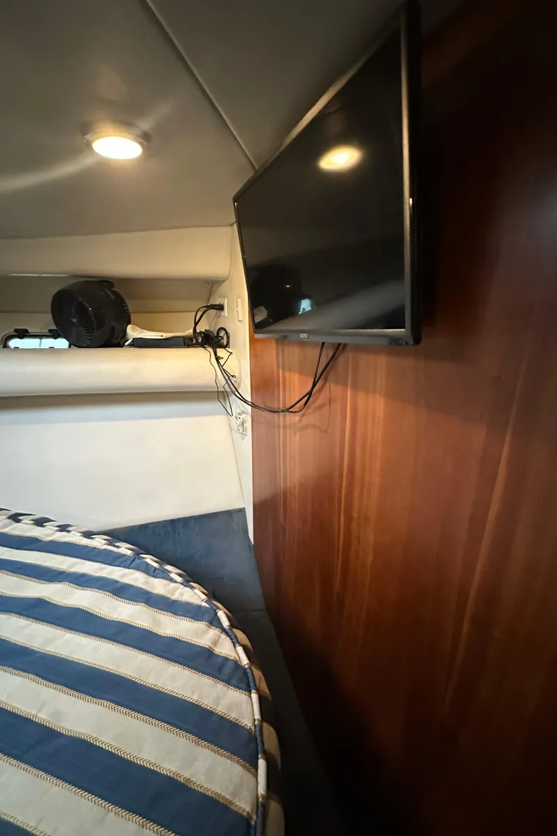Slide: The Image of Interior of 2002 Riviera 350 yacht with striped bedding and wall-mounted TV. - 26