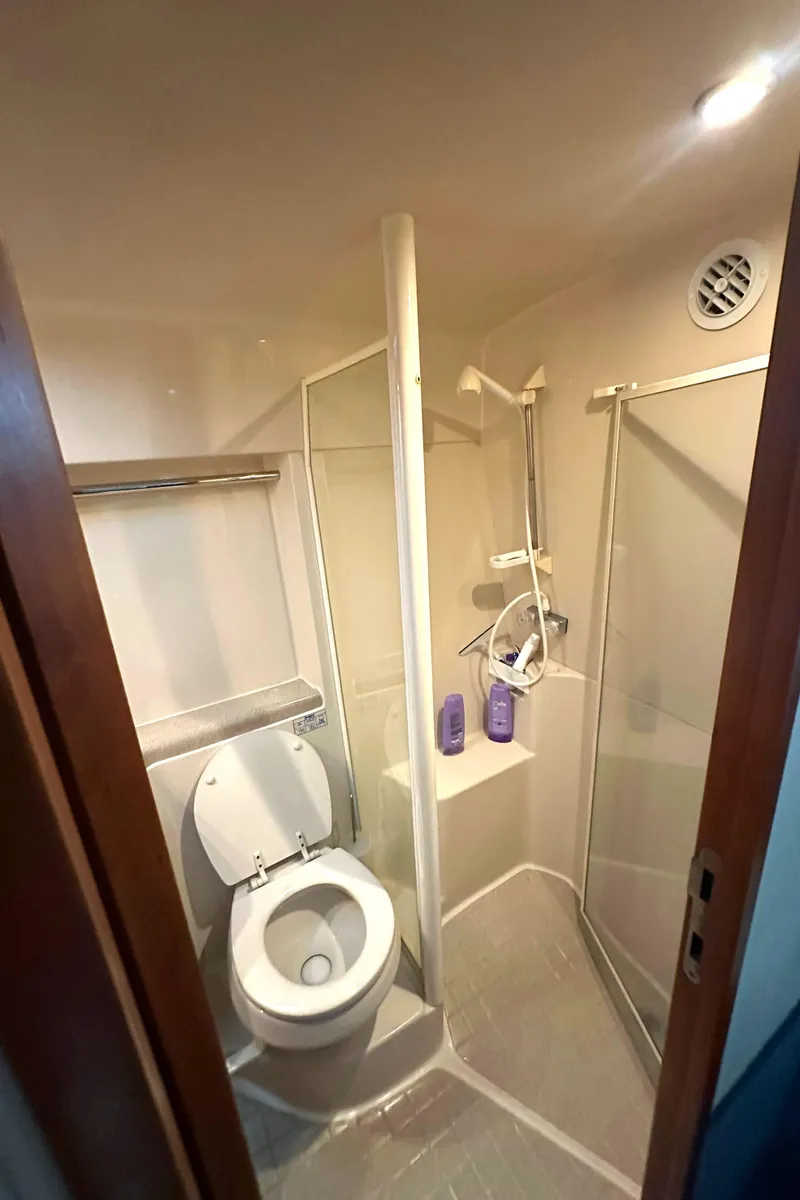 Slide: The Image of Compact bathroom in a 2002 Riviera 350 boat, featuring a toilet and shower. - 27