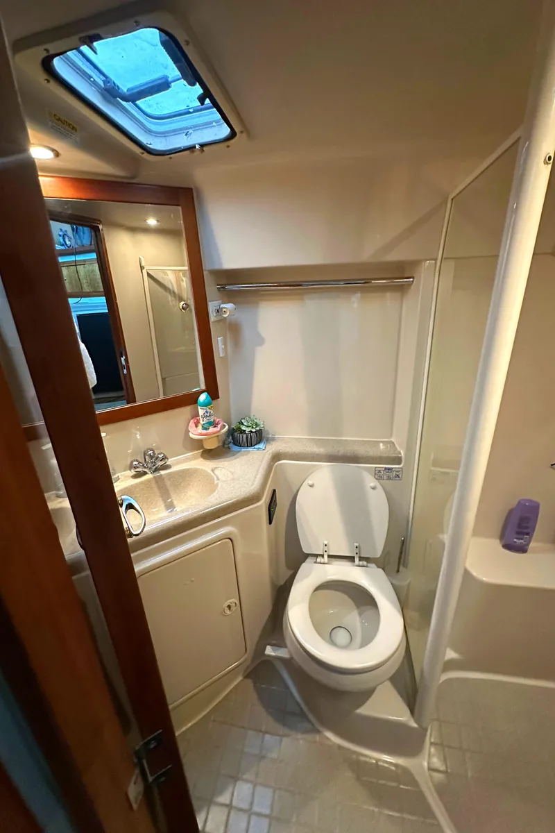 Slide: The Image of 2002 Riviera 350 yacht bathroom with toilet, sink, mirror, and shower. - 28