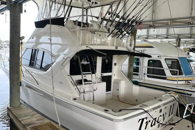 Slide: The Image of 2002 Riviera 350 yacht docked, featuring fishing rods and spacious deck area. - 3