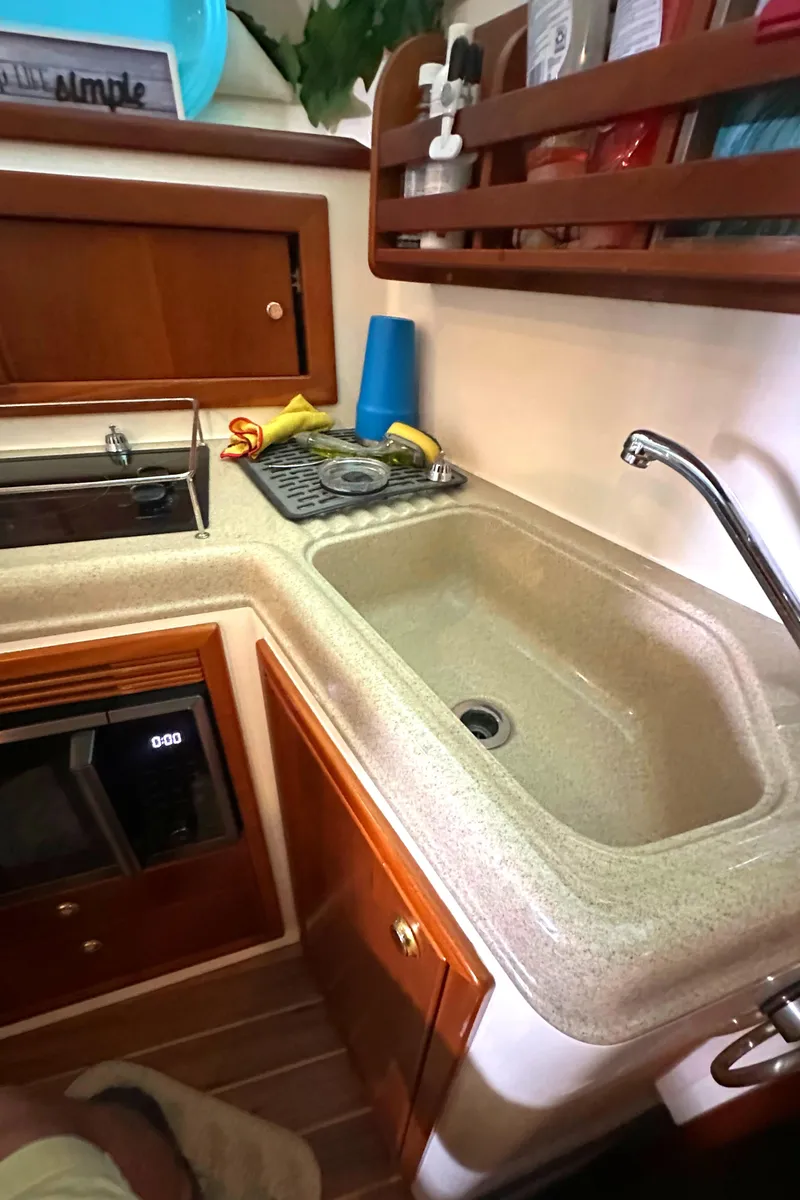 Slide: The Image of 2002 Riviera 350 yacht kitchen with sink, stove, and wooden cabinetry. - 32