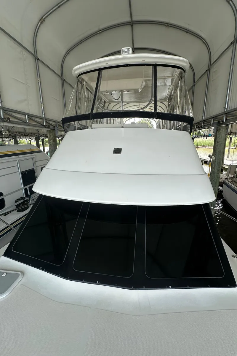 Slide: The Image of 2002 Riviera 350 yacht under a covered dock, showcasing sleek design and tinted windows. - 9