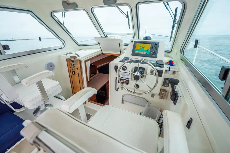 Slide: The Image of 2005 Back Cove Downeast Hardtop boat interior with steering wheel and navigation equipment. - 19