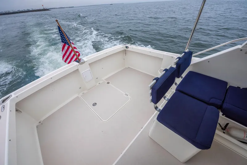 Slide: The Image of 2005 Back Cove Downeast Hardtop boat deck with American flag, cruising on open water. - 34