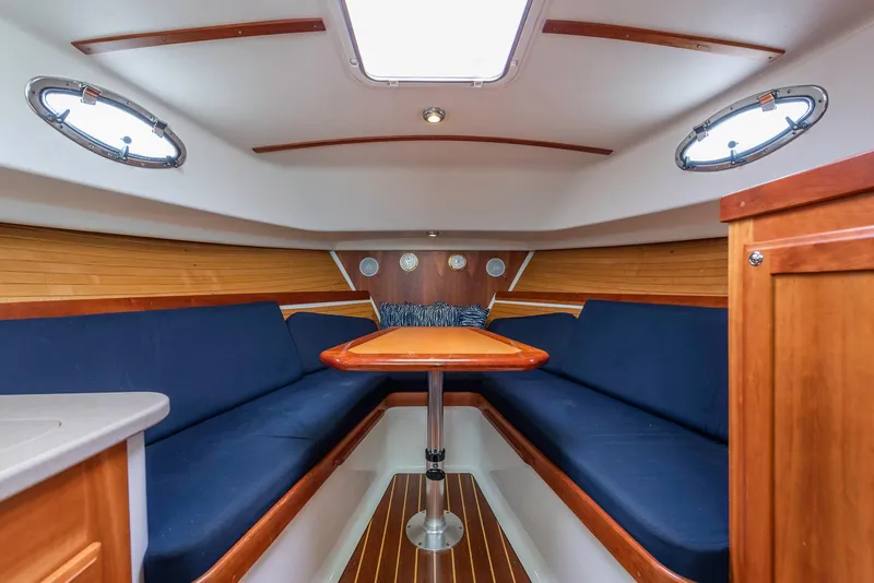 Slide: The Image of 2005 Back Cove Downeast Hardtop interior with blue seating and wooden table. - 6