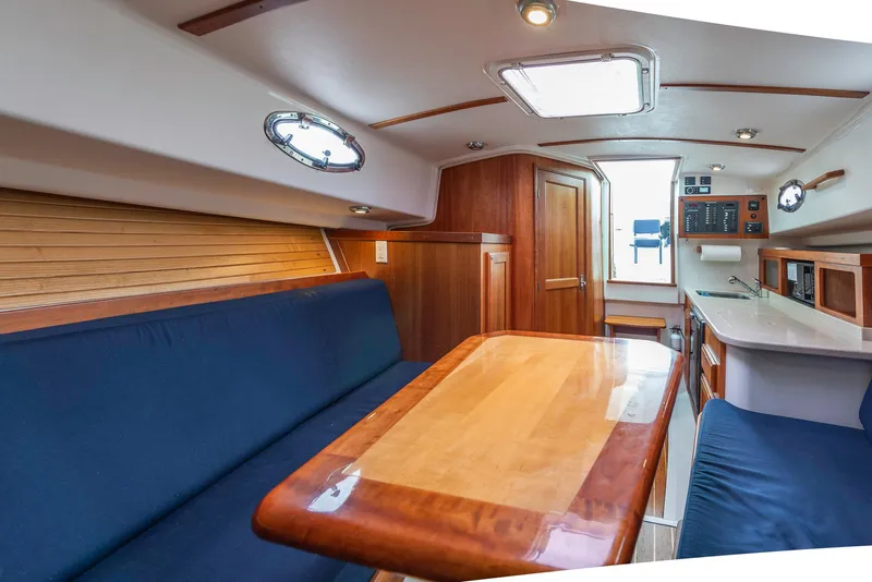 Slide: The Image of 2005 Back Cove Downeast Hardtop interior with wooden table, blue seating, and modern amenities. - 7