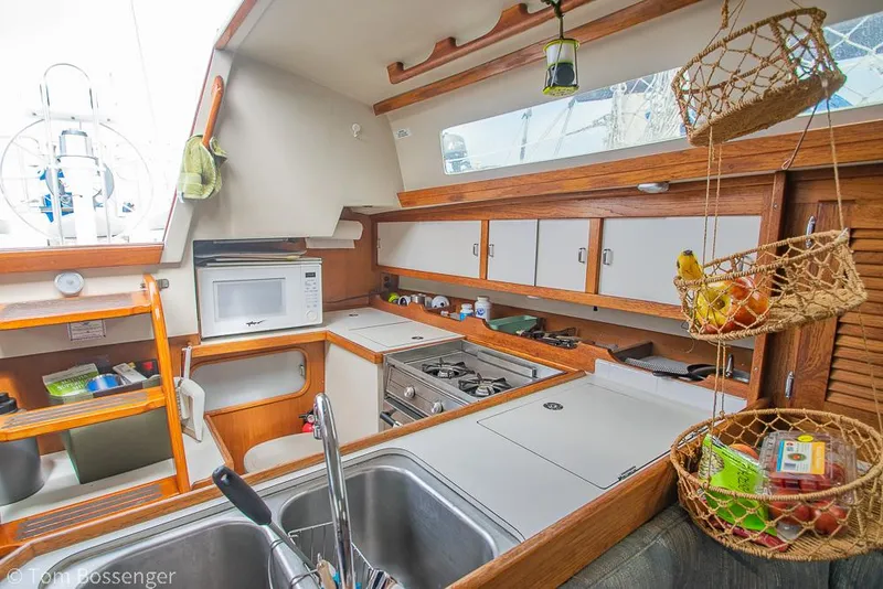 Slide: The Image of Interior of 1992 Catalina 36 sailboat kitchen with sink, stove, and hanging baskets. - 10