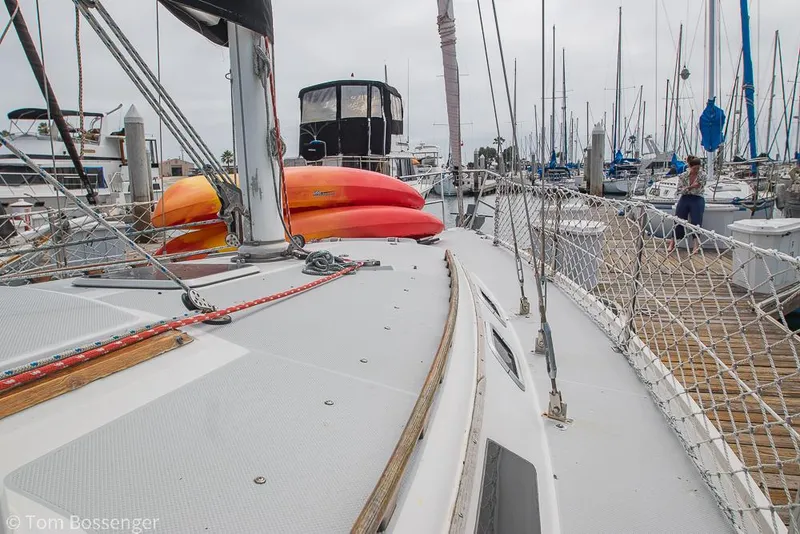Slide: The Image of 1992 Catalina 36 sailboat docked, featuring kayaks on deck, surrounded by marina boats. - 38