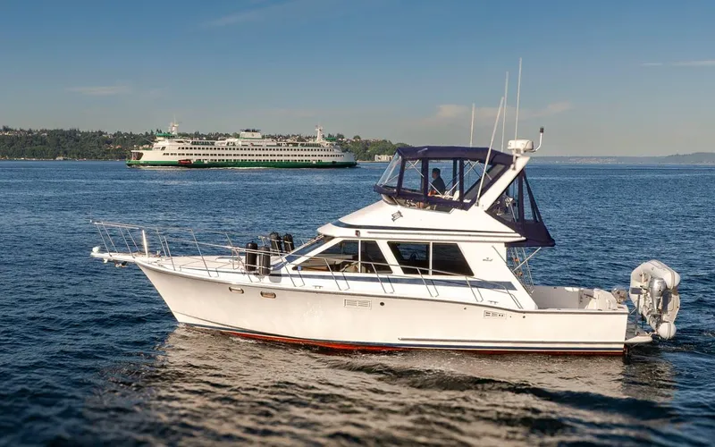 Slide: The Image of 1993 Tollycraft 40 Sport Sedan yacht cruising on a sunny day with a ferry in the background. - 2