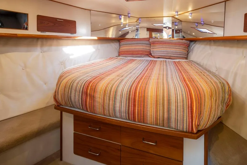 Slide: The Image of Cozy bedroom in 1993 Tollycraft 40 Sport Sedan with striped bedding and wooden storage drawers. - 21