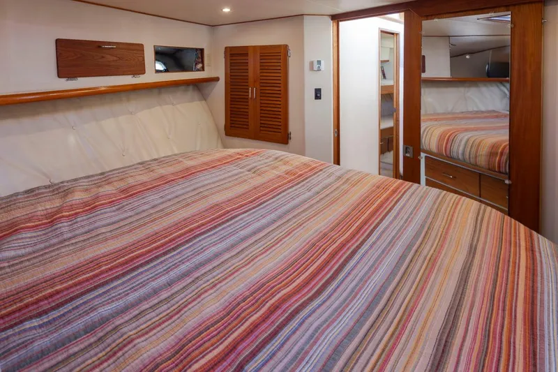 Slide: The Image of Interior of 1993 Tollycraft 40 Sport Sedan with striped bedding and wooden accents. - 22