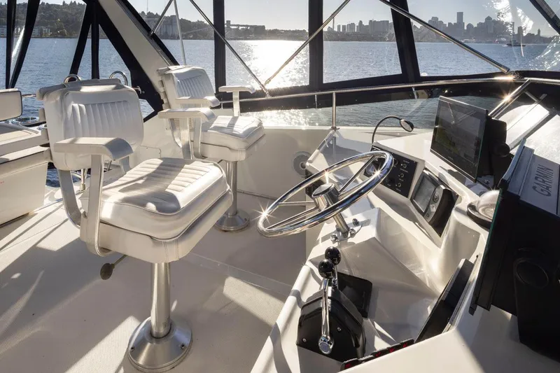 Slide: The Image of 1993 Tollycraft 40 Sport Sedan helm with dual captain chairs, overlooking scenic waterfront. - 29