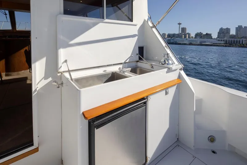 Slide: The Image of 1993 Tollycraft 40 Sport Sedan yacht with outdoor sink and fridge, city skyline in background. - 35