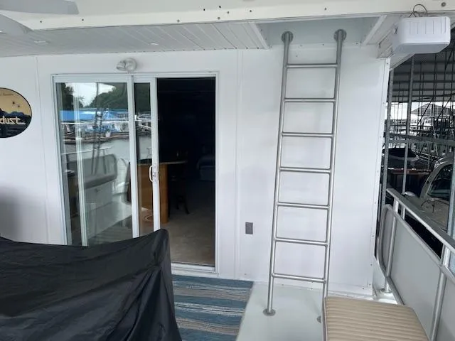 Slide: The Image of 2001 Stardust Cruisers houseboat with sliding glass door, ladder, and covered outdoor area. - 12