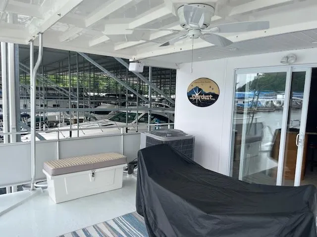 Slide: The Image of 2001 Stardust Cruisers houseboat deck with seating, ceiling fan, and marina view. - 13
