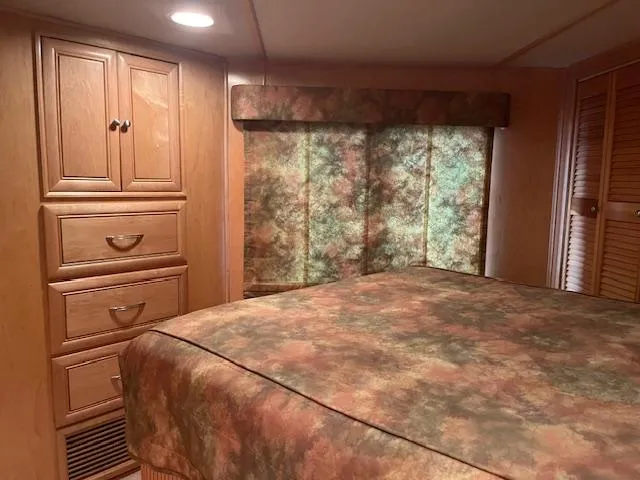 Slide: The Image of Cozy bedroom interior of 2001 Stardust Cruisers 18 x 103 houseboat with wood cabinetry and patterned bedding. - 36