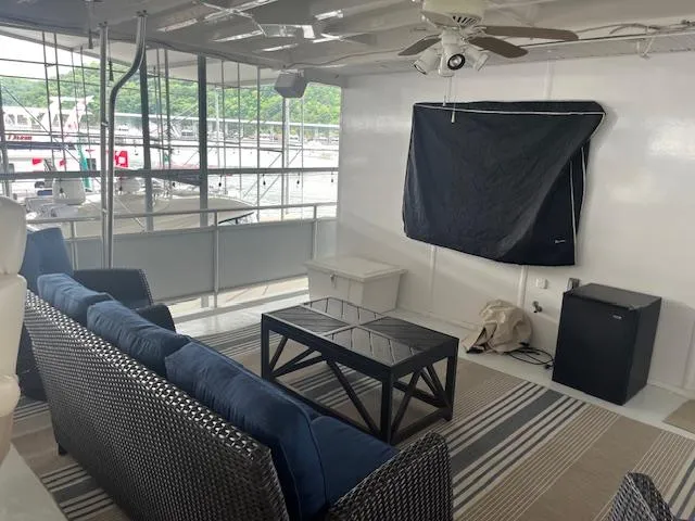 Slide: The Image of 2001 Stardust Cruisers houseboat interior with wicker furniture, ceiling fan, and covered TV. - 5